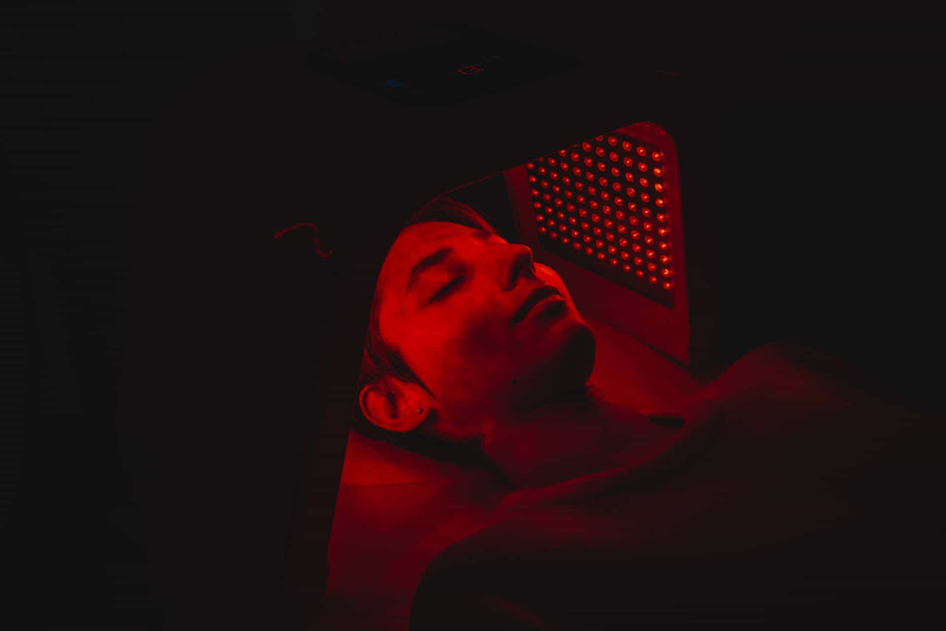 Small red light therapy room with warm LED glow and espresso wood floor.