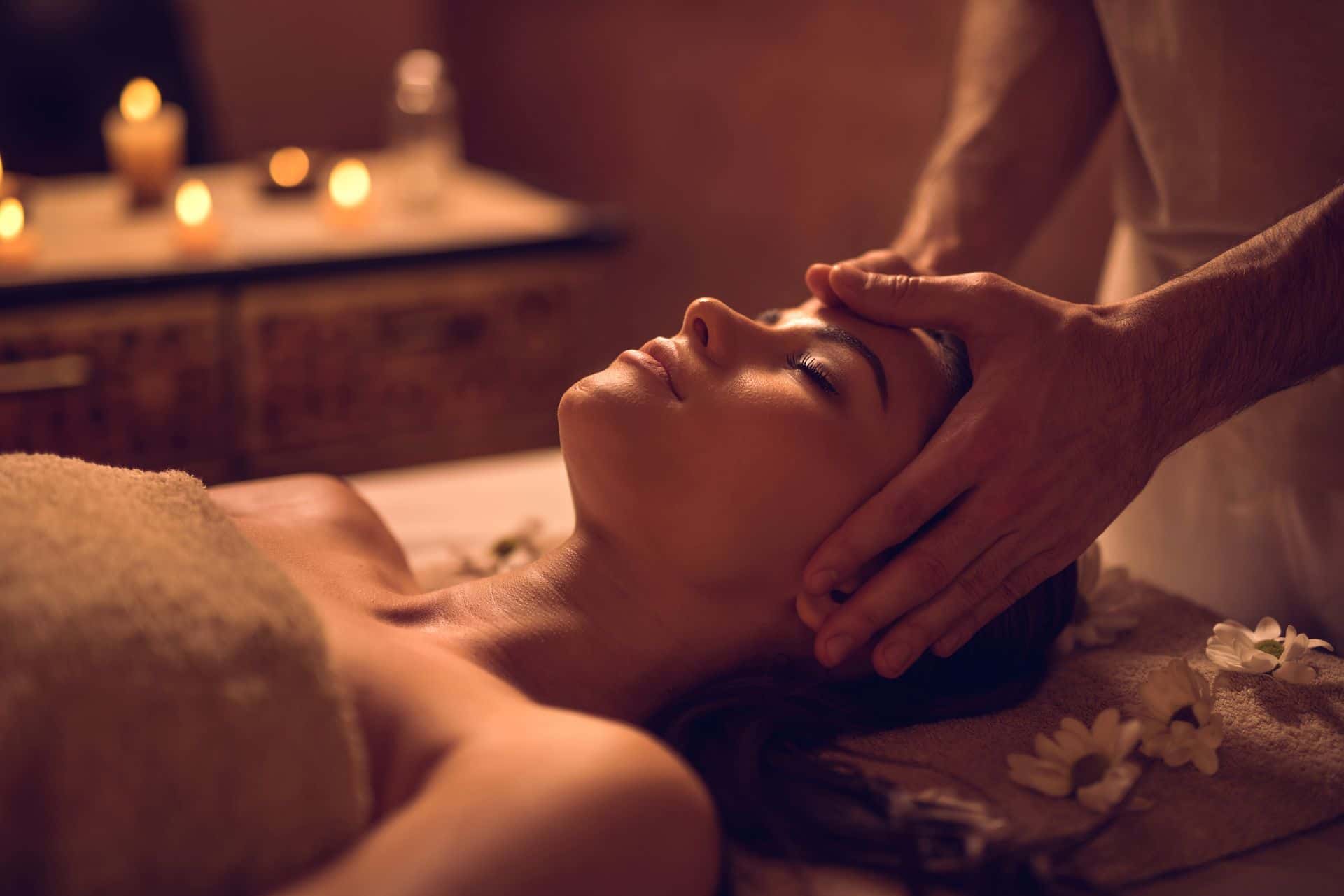 Massage therapist applying professional pressure over a draped client upper back.