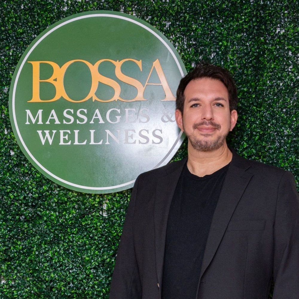 Billy Bossa, owner and licensed massage therapist, in front of the Bossa Massages and Wellness sign.