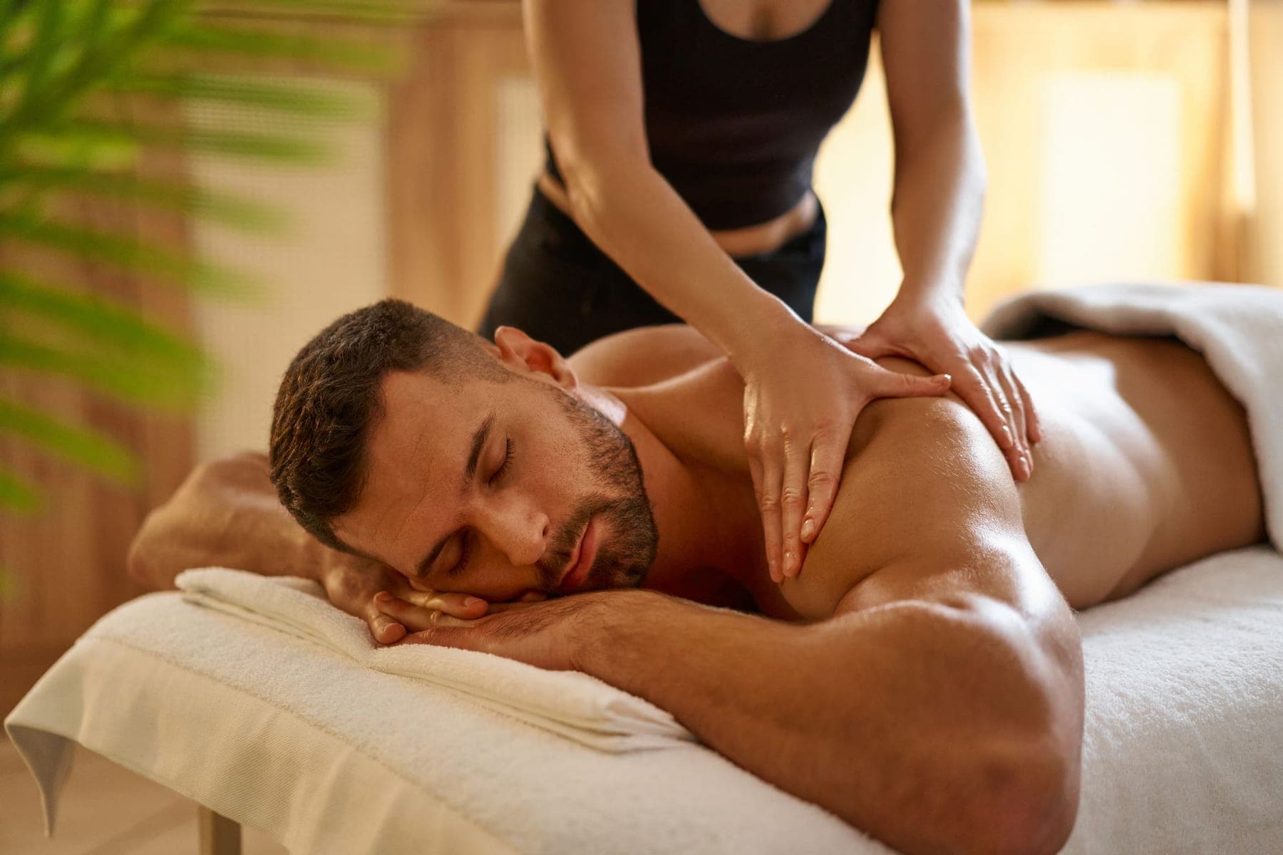 Hot stones arranged on a folded towel beside a massage table.