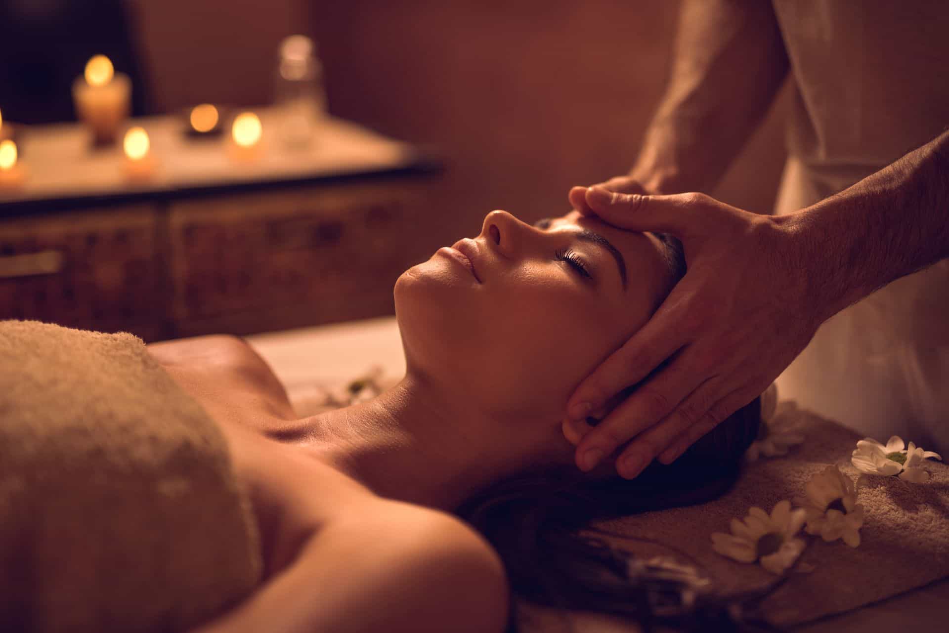 Massage therapist applying professional pressure over a draped client upper back.